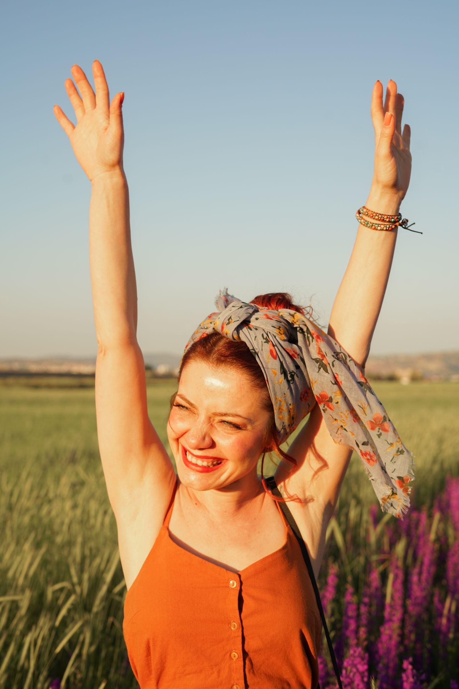 Femme souriante, bras levés, fière d'elle en extérieur